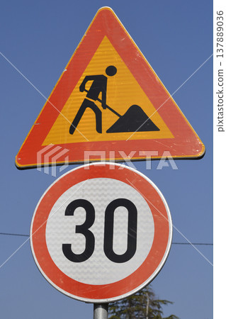 Road work and speed limit traffic signs against blue sky Road work and speed limit traffic signs against blue sky 137889036