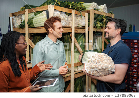 Produce workers discussing logistics holding tablet in warehouse Produce workers discussing logistics holding tablet in warehouse 137889062