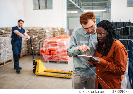 Diverse warehouse colleagues using digital tablet for inventory management 137889084
