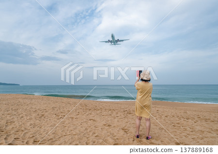 This image captures two powerful concepts: the rise of solo travel in later life and the global phenomenon of planespotting at one of the world's most unique aviation locations. Mai Khao Beach is This image captures two powerful concepts: the rise of solo travel in later life and the global phenomenon of planespotting at one of the world's most unique aviation locations. Mai Khao Beach is 137889168