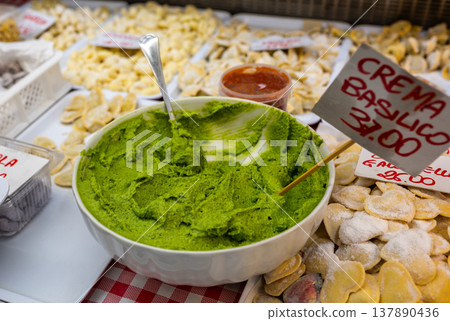 Genoa, liguria, italy. May 18, 2024. Basil cream pesto in white bowl at an italian market stall, surrounded by assorted fresh handmade pastas for sale and tasting Genoa, liguria, italy. May 18, 2024. Basil cream pesto in white bowl at an italian market stall, surrounded by assorted fresh handmade pastas for sale and tasting 137890436