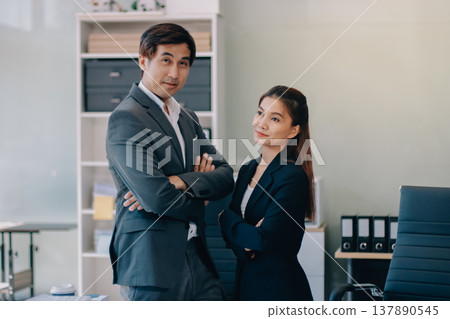 Portrait of a happy Asian business couple standing together. Young professional man and woman smiling in studio. Corporate teamwork concept Portrait of a happy Asian business couple standing together. Young professional man and woman smiling in studio. Corporate teamwork concept 137890545