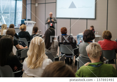 Attentive audience listening to speaker during business seminar presentation in modern conference room Attentive audience listening to speaker during business seminar presentation in modern conference room 137891491