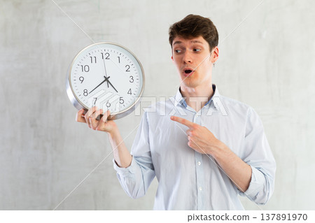 Man with a round big clock in his hands expresses various emotions Man with a round big clock in his hands expresses various emotions 137891970