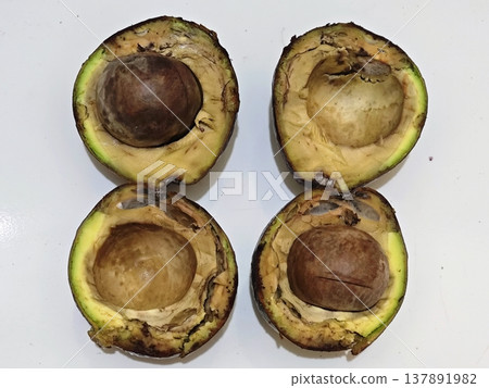 Rotten avocado halves with seeds on a white background Rotten avocado halves with seeds on a white background 137891982