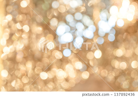 Golden bokeh lights with blurred circular highlights and warm tone creating an abstract light pattern suitable for luxury background use. 137892436