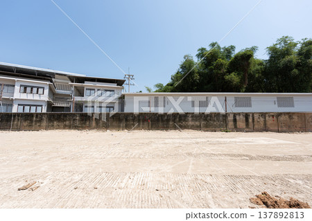 Empty construction site with cleared ground and building structure in background. Wide open land prepared for development and construction work. Empty construction site with cleared ground and building structure in background. Wide open land prepared for development and construction work. 137892813