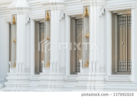 White temple windows and door with traditional Thai architectural details and symmetry creating a clean exterior design that reflects cultural heritage and structure. White temple windows and door with traditional Thai architectural details and symmetry creating a clean exterior design that reflects cultural heritage and structure. 137892828