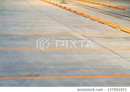Empty parking space with orange lines on a concrete surface showing a clean layout and organized structure for vehicle positioning. Empty parking space with orange lines on a concrete surface showing a clean layout and organized structure for vehicle positioning. 137892831
