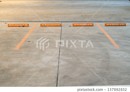 Empty parking space with orange lines on a concrete surface showing a clean layout and organized structure for vehicle positioning. Empty parking space with orange lines on a concrete surface showing a clean layout and organized structure for vehicle positioning. 137892832