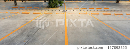 Empty parking space with orange lines on a concrete surface showing a clean layout and organized structure for vehicle positioning. Empty parking space with orange lines on a concrete surface showing a clean layout and organized structure for vehicle positioning. 137892833