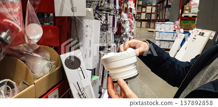 A customer holds a paint tray and brushes while shopping in a hardware store aisle. Concepts of home improvement, DIY renovation, consumer choice, and retail shopping behavior. A customer holds a paint tray and brushes while shopping in a hardware store aisle. Concepts of home improvement, DIY renovation, consumer choice, and retail shopping behavior. 137892858