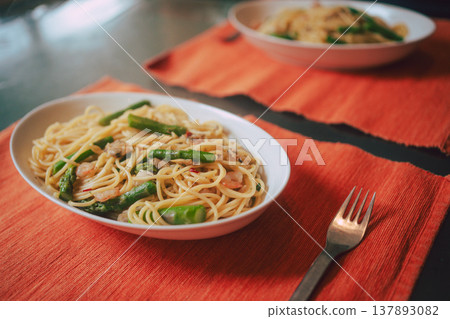 Asparagus and seafood pasta served on an orange mat. Asparagus and seafood pasta served on an orange mat. 137893082