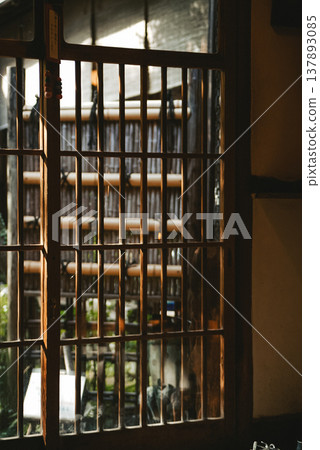 柔和的陽光透過日式房屋的格子門和花園裡的竹籬笆灑進來。 柔和的陽光透過日式房屋的格子門和花園裡的竹籬笆灑進來。 137893085
