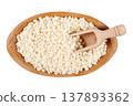 Raw Dried white corn used in the preparation of canjica, Brazilian corn dessert, in a wooden bowl with a small measuring scoop, isolated on a white background 137893362