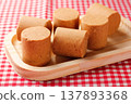 Pacoca, a traditional Brazilian sweet made from peanuts in a cylindrical shape, served on a wooden tray on a checkered tablecloth 137893368