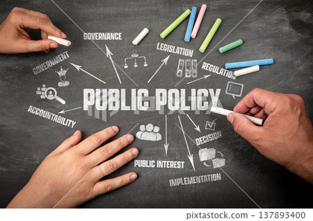 Public Policy Concept. Human Hands with Pieces of Chalk on a Dark Chalkboard Background Public Policy Concept. Human Hands with Pieces of Chalk on a Dark Chalkboard Background 137893400