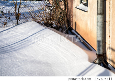 Winter Snow Accumulation Along House Wall And Metal Drainpipe Winter Snow Accumulation Along House Wall And Metal Drainpipe 137893411
