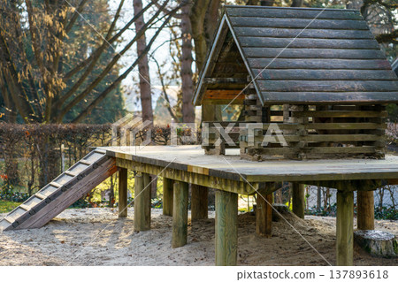 Wooden playhouse with ramp in sandbox playground area. Natural materials play structure for kids, outdoor recreation and family friendly park concept Wooden playhouse with ramp in sandbox playground area. Natural materials play structure for kids, outdoor recreation and family friendly park concept 137893618