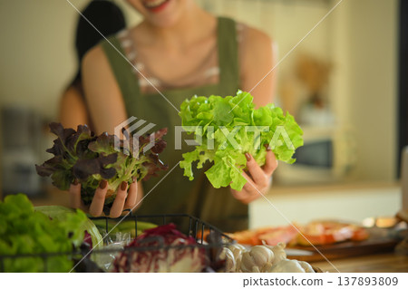 Closeup Woman selecting fresh green lettuce and vegetables in a cozy home kitchen Closeup Woman selecting fresh green lettuce and vegetables in a cozy home kitchen 137893809