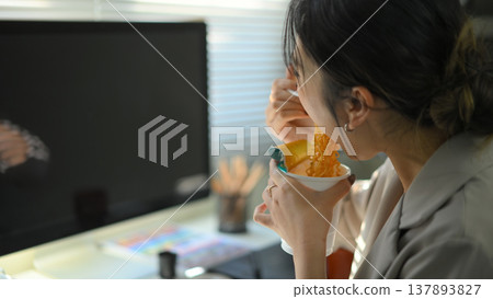 Closeup young woman eating instant noodles in office workplace Closeup young woman eating instant noodles in office workplace 137893827