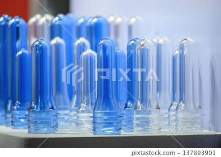 Close-up of a group of clear and blue PET plastic bottle preforms ready for the blow molding process. Close-up of a group of clear and blue PET plastic bottle preforms ready for the blow molding process. 137893901