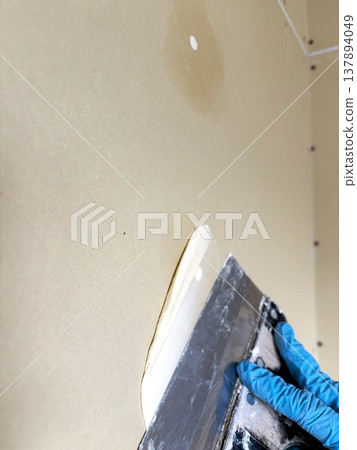 Applying putty to screw holes in drywall; the process of applying putty by hand. Applying putty to screw holes in drywall; the process of applying putty by hand. 137894049