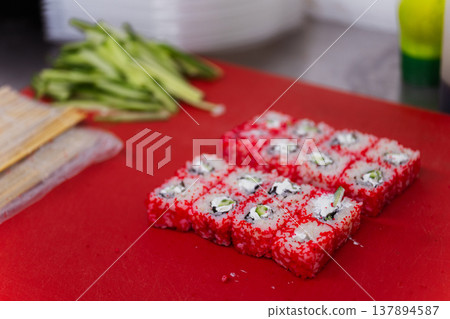 Vibrant Red Tobiko Rolls On Red Cutting Board Next To Avocado And Knife, Bright Roe Texture And Neat Vibrant Red Tobiko Rolls On Red Cutting Board Next To Avocado And Knife, Bright Roe Texture And Neat 137894587
