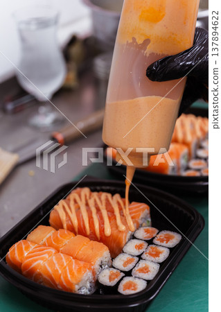 Chef Drizzling Sauce Over Salmon Rolls With Squeeze Bottle, Creamy Spicy Mayo Applied As Finishing Chef Drizzling Sauce Over Salmon Rolls With Squeeze Bottle, Creamy Spicy Mayo Applied As Finishing 137894622