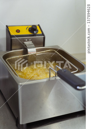 Deep Fryer Bubbling With Hot Oil, Stainless Steel Basket Immersed In Golden Oil, Steam Rising 137894628