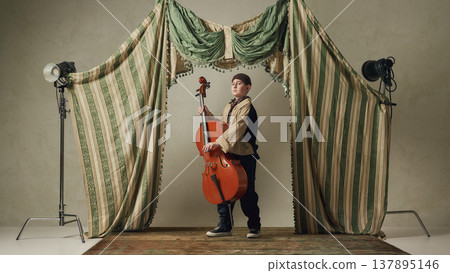 Teen boy holding cello on stage confident classical music portrait. Teen boy holding cello on stage confident classical music portrait. 137895146