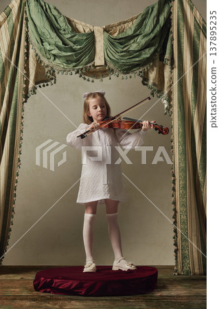 Little girl playing violin on small stage in white dress. Little girl playing violin on small stage in white dress. 137895235