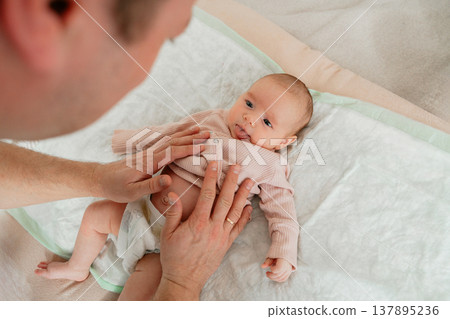 Father interacting and playing with newborn baby at home. Emotional bonding, early development and joyful parenting moment. 137895236