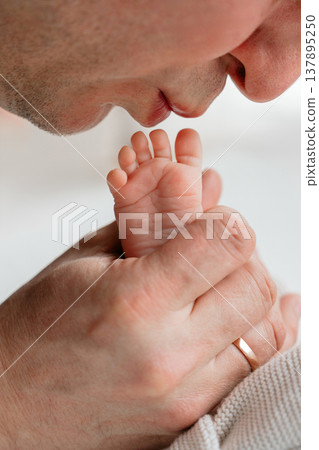Father gently kissing tiny newborn baby feet. Emotional bonding moment expressing love, care, and connection in early days of parenthood. Soft lifestyle family scene. Father gently kissing tiny newborn baby feet. Emotional bonding moment expressing love, care, and connection in early days of parenthood. Soft lifestyle family scene. 137895250