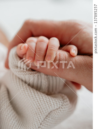 Tender moment of bonding between baby and parent. Minimalistic composition with soft textures and cozy clothing emphasizes intimacy and safety. Perfect for parenting and family themes. Tender moment of bonding between baby and parent. Minimalistic composition with soft textures and cozy clothing emphasizes intimacy and safety. Perfect for parenting and family themes. 137895257