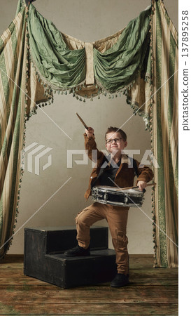 Little boy playing snare drum on vintage stage confident child musician performance scene. 137895258
