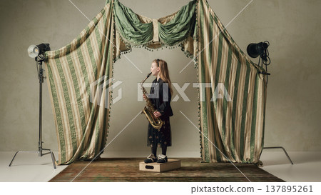 Young girl playing saxophone on studio stage with lighting equipment creative music performance. Young girl playing saxophone on studio stage with lighting equipment creative music performance. 137895261