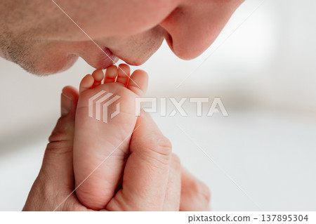 Close-up of father holding and kissing baby feet. Concept of fatherhood, tenderness, and family bonding. Ideal for parenting, family values, and emotional storytelling. Close-up of father holding and kissing baby feet. Concept of fatherhood, tenderness, and family bonding. Ideal for parenting, family values, and emotional storytelling. 137895304