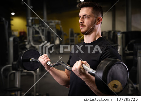 Fitness and health concept. A fit young man works out in a modern gym. Athletic man doing exercise. Fitness and health concept. A fit young man works out in a modern gym. Athletic man doing exercise. 137895729