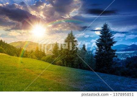 day meet night on mountain hay field. sun and moon over alpine countryside summer landscape with green valley behind the woods on the grassy slope at twilight. cloudy sky. epic highland background day meet night on mountain hay field. sun and moon over alpine countryside summer landscape with green valley behind the woods on the grassy slope at twilight. cloudy sky. epic highland background 137895851