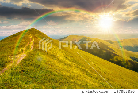 sunset over gorgeous summer landscape. mountain path through grassy meadow on steep hillside. scenic alpine scenery with trail direction turns uphill to the sky with clouds. weather with rainbow sunset over gorgeous summer landscape. mountain path through grassy meadow on steep hillside. scenic alpine scenery with trail direction turns uphill to the sky with clouds. weather with rainbow 137895856