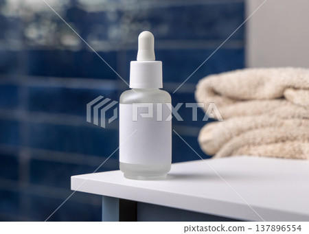 Dropper bottle with blank label near beige bath towels in blue bathroom, cosmetic mockup Dropper bottle with blank label near beige bath towels in blue bathroom, cosmetic mockup 137896554