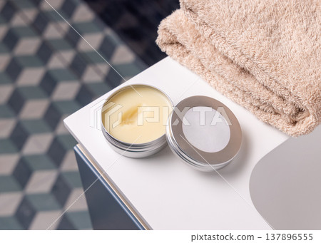 Opened handmade lip balm tin cosmetic mockup in blue bathroom. Metal lid with round blank label Opened handmade lip balm tin cosmetic mockup in blue bathroom. Metal lid with round blank label 137896555