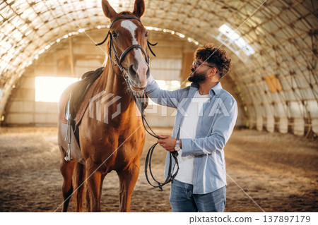 Stroking the animal with his hand. Man is with horse in the hangar Stroking the animal with his hand. Man is with horse in the hangar 137897179