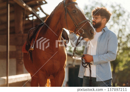 Looking at the animal. Guy is with horse on the farm Looking at the animal. Guy is with horse on the farm 137897211