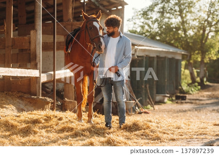 Guy is with horse on the farm Guy is with horse on the farm 137897239