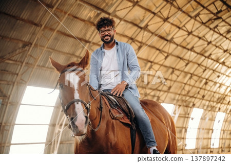 Rider is on the animal. Man is with horse in the hangar Rider is on the animal. Man is with horse in the hangar 137897242