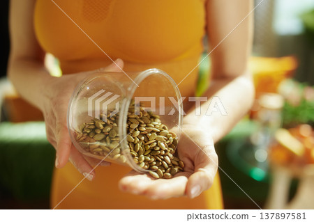 Woman Pouring Fresh Pumpkin Seeds into Her Hand Woman Pouring Fresh Pumpkin Seeds into Her Hand 137897581