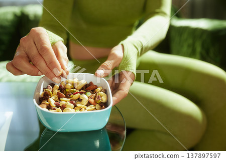 Athletic Woman Enjoying a Plant-Based Nut Snack Athletic Woman Enjoying a Plant-Based Nut Snack 137897597