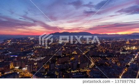 Vibrant Malaga cityscape at dusk with illuminated skyline, iconic tower, and scenic mountainous backdrop. urban, architectural, or travel-themed projects. Malaga Spain Vibrant Malaga cityscape at dusk with illuminated skyline, iconic tower, and scenic mountainous backdrop. urban, architectural, or travel-themed projects. Malaga Spain 137897762